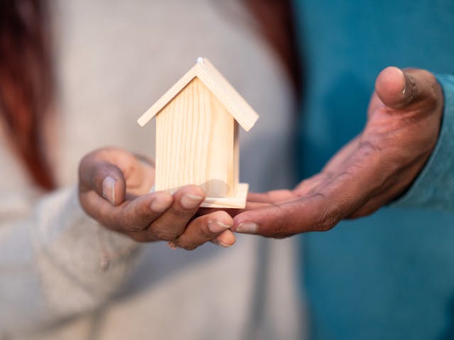 two%20people%20holding%20a%20figure%20of%20a%20house